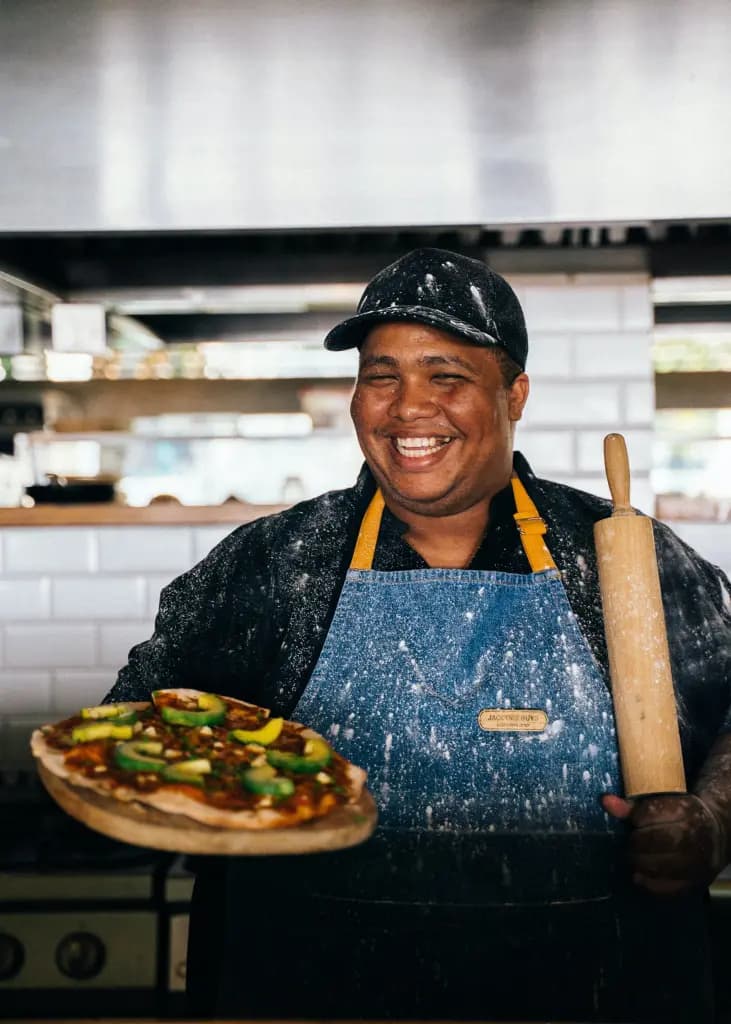 Restaurant chef smiling holding a pizza